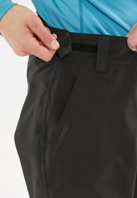 Schwarze, wasserdichte Hose mit einem verstellbaren Klettverschlussbund, einem eleganten Design und einem sichtbaren "WPRO 10000"-Label am unteren Bein.