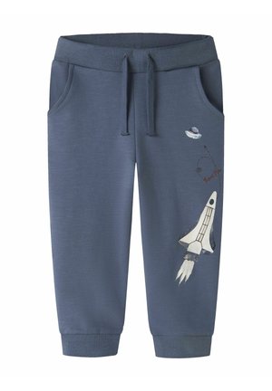 Pantalon de jogging bleu pour enfants avec poches avant, taille ajustable et imprimé à thème spatial avec fusée et OVNI sur la jambe droite.