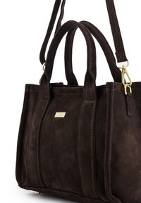 Sac à main en daim marron avec ferrures dorées, double poignée supérieure et une bandoulière réglable. Présente des coutures évidentes et une forme rectangulaire.