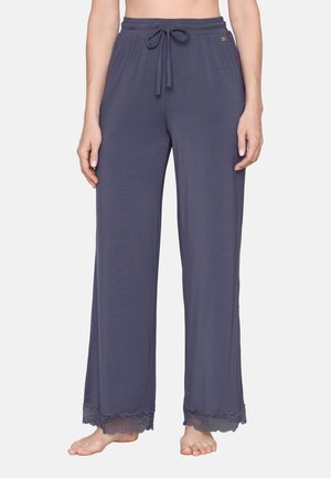 Losse donkergrijze broek met een elastische tailleband en trekkoord, met kantafwerking aan de brede zomen, blootsvoets gedragen op een neutrale achtergrond.