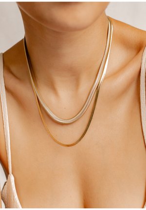 Drei geschichtete Halsketten mit silbernen und goldenen Metallsträngen in einem glatten, eleganten Design. Die Ketten passen eng am Hals an.