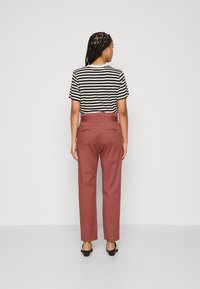 Gestreiftes Kurzarmoberteil in Schwarz und Weiß. Hochtaillierte, lässig geschnittene Hose in verwaschenem Rosé. Einfaches Design, keine sichtbaren Muster oder Beschläge.