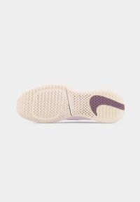 Semelle d'une chaussure de sport de couleur claire avec des motifs de bande de roulement ondulés et un logo Nike swoosh violet foncé près du talon.