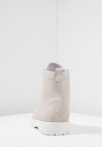 Stivale alla caviglia in camoscio beige con suola in gomma bianca, linguetta sul retro e texture liscia. Design semplice, senza motivi o decorazioni visibili.