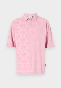 Pink polo shirt featuring a textured pattern with repeated motifs. Short sleeves and a classic collar with buttons in the front.