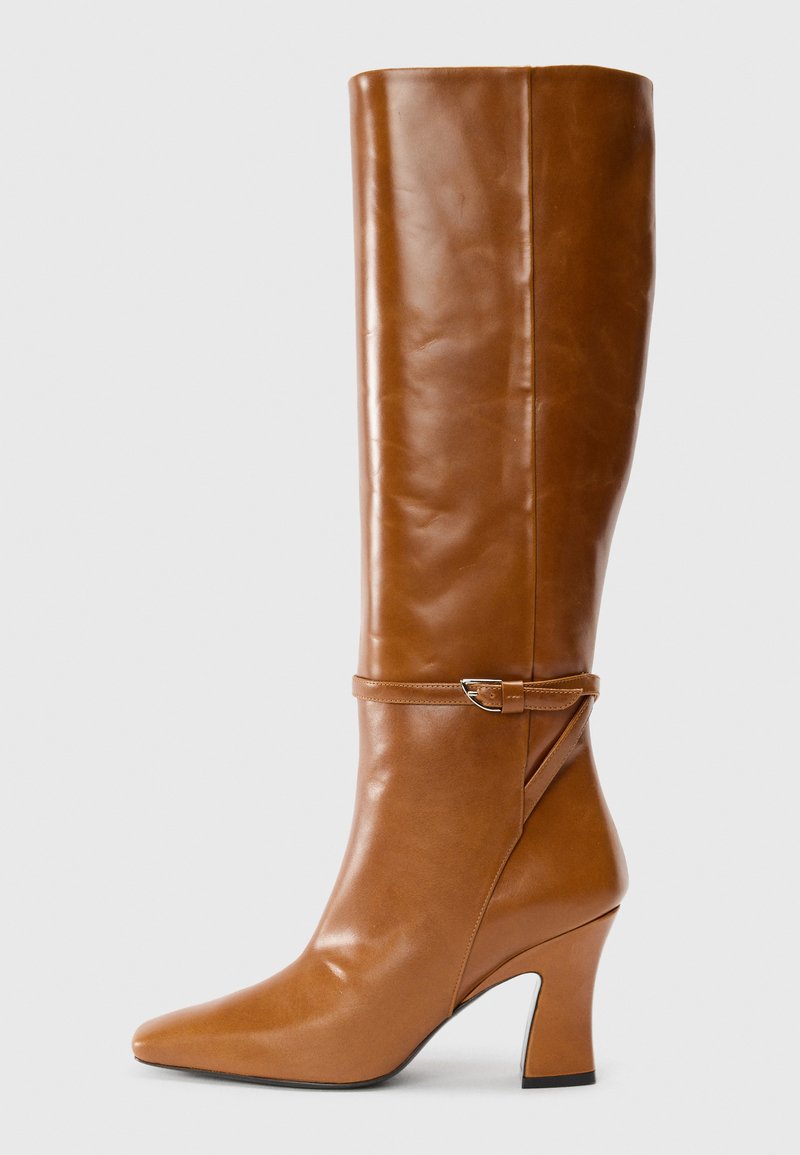 Bota de cuero marrón hasta la rodilla con punta afilada y un diseño elegante. Presenta un detalle de hebilla y un tacón bloque medio para mayor estabilidad.
