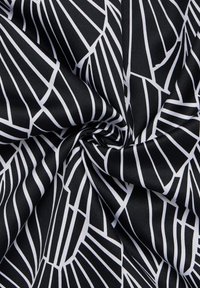 Tissu noir arborant des lignes blanches géométriques audacieuses dans un motif. La texture semble lisse et légèrement brillante, avec une finition satinée.