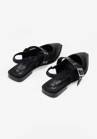 Scarpe slingback nere con punta a punta e tacco quadrato basso. Realizzate in materiale sintetico liscio, presentano dettagli in argento e una fibbia.