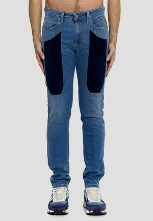 Jeans blu con pannelli in corduroy blu scuro sulle cosce, vestibilità slim, cinque tasche e classica texture in denim. Abbinati a sneaker bianche e blu.
