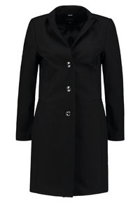 Manteau noir sur mesure avec col cranté, tissu texturé, boutonnage simple et quatre boutons brillants. Comprend deux poches latérales.