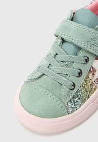 Světlé zelené semišové tenisky s třpytivým bokem, šněrovací, s růžovou gumovou podrážkou. Mají suchý zip pro snadné zapínání.
