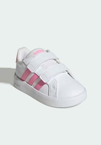 Bílá sportovní bota z umělých materiálů s růžovými pruhy, s texturovaným textilním jazykem a dvěma pásky na suchý zip k zavírání. Ozdobena logem.