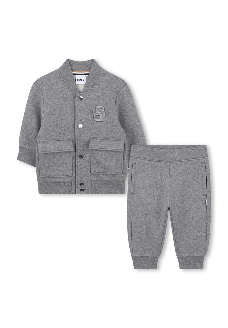 Szary dziecięcy kurtka z długim rękawem i guzikami, posiadająca dwie przednie kieszenie oraz dopasowane spodnie z elastycznymi mankietami, z wytłoczonym logo na klatce piersiowej kurtki.