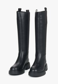 Zwarte leren kniehoge laarzen met een gladde textuur, chunky rubberen zolen en trekriemen aan de bovenrand voor gemakkelijk aan- en uittrekken.