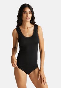 Černý bezramínkový top s vlnitým krajkovým výstřihem, vyrobený z hladké tkaniny. V páru s odpovídajícími černými spodními kalhotkami s krajkovým lemem.