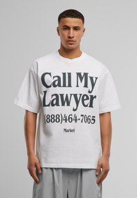Hvit bomull t-skjorte med oversized passform, med svart tekst: "Ring advokaten min (888)464-7065" og "Market" logo nederst.