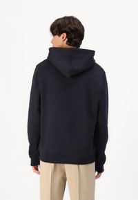 Felpa con cappuccio blu navy, dal fit comodo, con polsini e fondo a costine. Il tessuto sembra morbido con una superficie liscia. Vista dal retro.