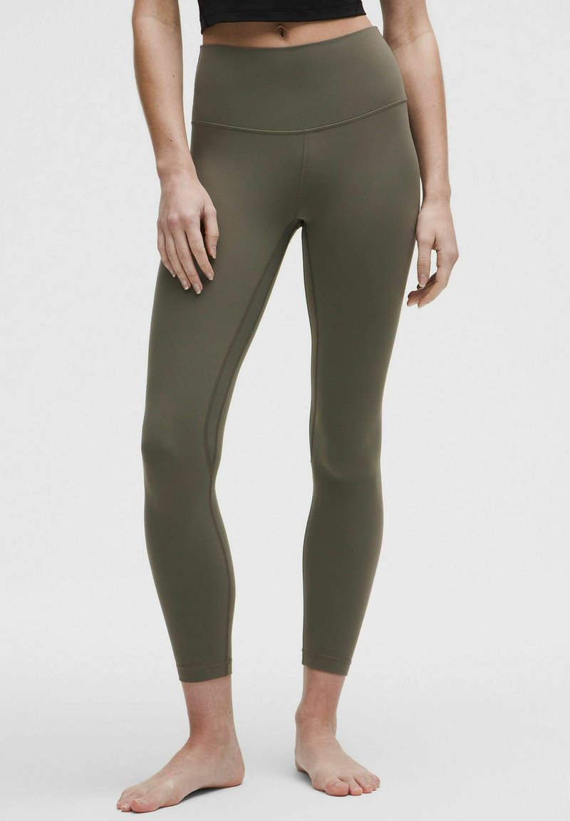 Olive green leggings with a high waistband, made from a stretchy fabric. Features flat seams and a fitted design, highlighting form.