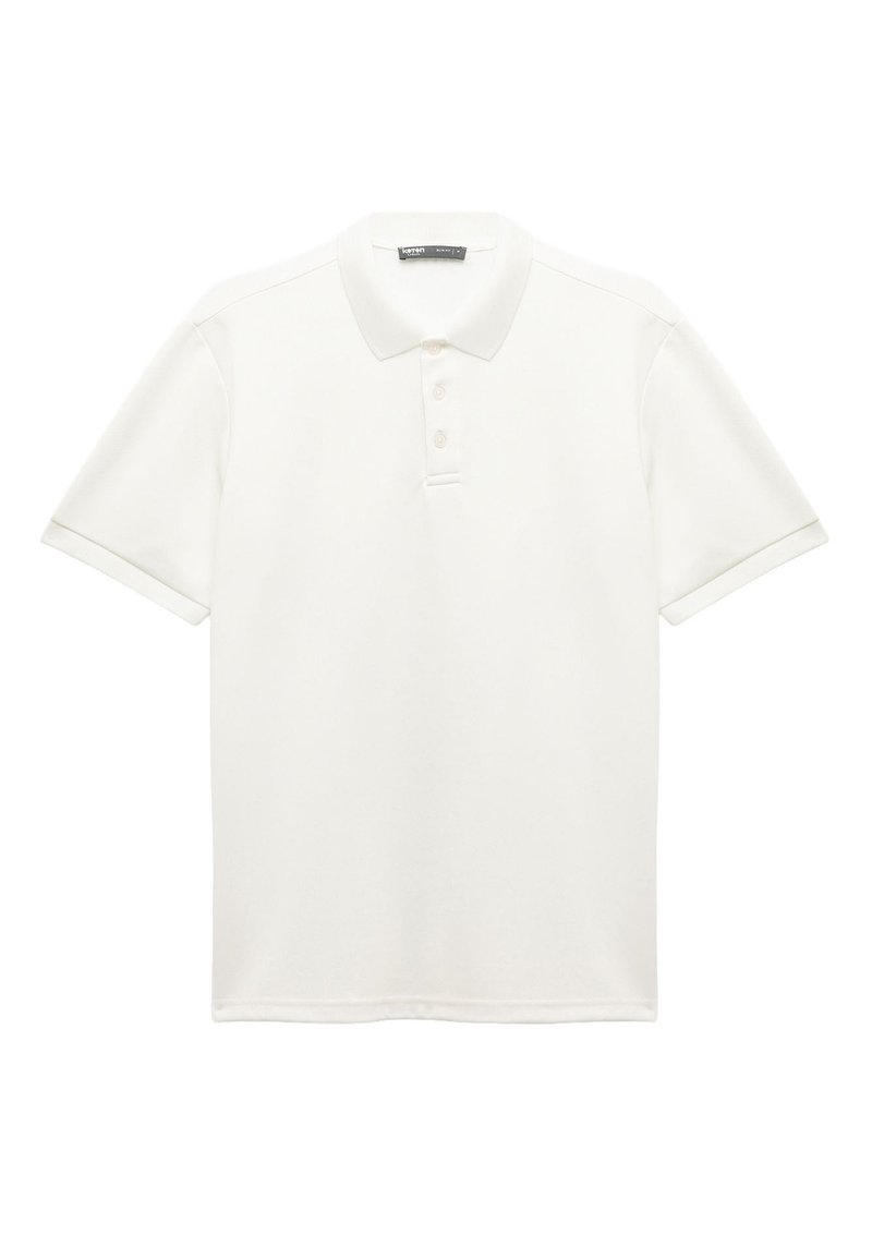 Polo shirt blanc en tissu texturé. Doté d'un col classique, d'une patte de boutonnage à trois boutons et de manches courtes avec des bords à retrousser.