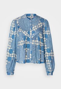 Blå quiltet bluse med knappestolpe, lange ermer og geometriske mønstre av lyseblå og hvite sirkler og diamanter. Teksturert stoff.