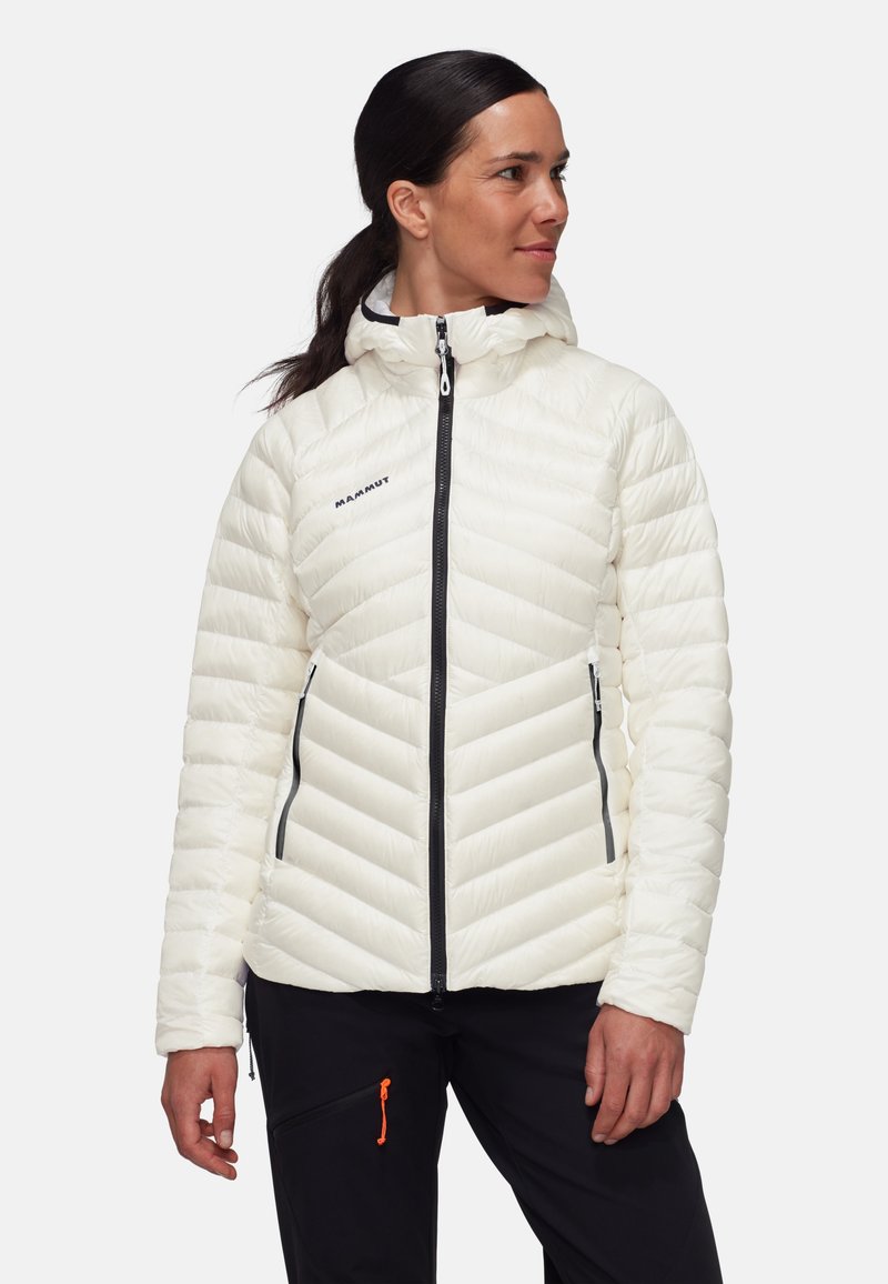 Giacca bianca isolata con cappuccio, caratterizzata da un design a rombi trapuntato, zip nere e un logo sul petto.