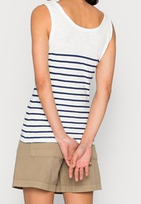 Gestreiftes Tanktop in Weiß und Marineblau, aus leichtem Stoff, mit rundem Ausschnitt und lockerer Passform, kombiniert mit Khakishorts.