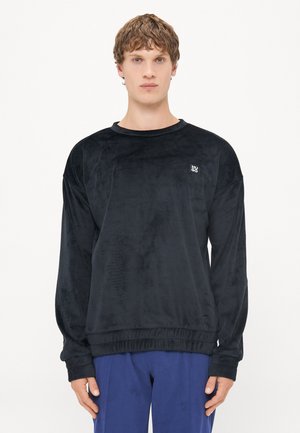 Schwarzes Fleece-Sweatshirt mit gerippten Bündchen und Saum. Verfügt über ein kleines Logo auf der Brust. Weicher Stoff und lockerer Schnitt.