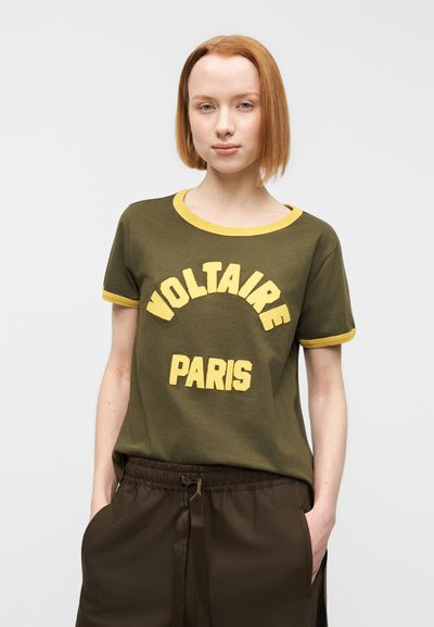 Πράσινο ελιάς T-shirt με κίτρινο ριμπ γιακά και μανσέτες, με έντονη κίτρινη εκτύπωση: "VOLTAIRE" πάνω από το "PARIS." Μαλακή υφή υφάσματος.
