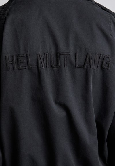 Fekete ruházat, amelyen hímzett "HELMUT LANG" felirat található a hátsó részen, sima anyag, puha textúrával és minimalista dizájnnal.