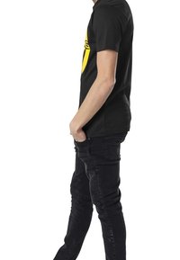 Zwart t-shirt met korte mouwen en een grote gele afbeelding op de voorkant. Gekozen in combinatie met donkere jeans, met een slim fit en textuurpanelen.