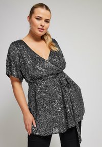 Top nero con paillettes, scollatura a V profonda, maniche corte e vita aderente. Presenta un dettaglio a fiocco e una superficie texturizzata e scintillante.