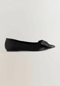 Ballerines noires avec un bout pointu et un accent en nœud. Fabriquées en cuir lisse, elles présentent une semelle plate et un design épuré.