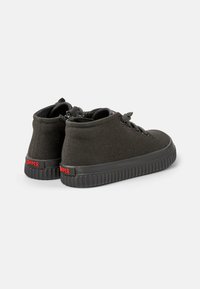 Sneaker alte nere con tomaia in rete testurizzata, lacci rotondi e suola in gomma con design scanalato e marchio rosso sul tallone.