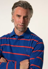 Blå randig polo t-shirt med röda ränder, med en klassisk krage och en liten logga på vänster sida. Mjuk tygkvalitet.