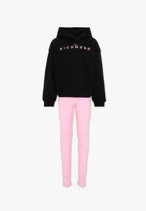 Zwarte hoodiesweater met roze tekst "John Richmond" gecombineerd met lichtroze slim-fit broek op een witte achtergrond.
