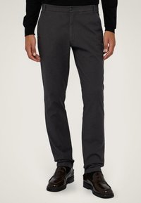 Tmavě šedé kalhoty slim fit, vyrobené z lehkého materiálu. Mají zapínání na knoflík a boční kapsy, nošeny s tmavými mokasíny.