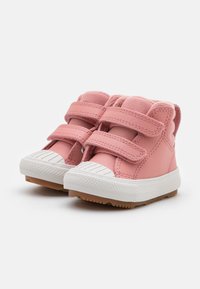 Zapatillas altas de cuero rosa con dos tiras de velcro, puntera de goma blanca, suelas texturizadas y forro suave. Ideales para un look casual.