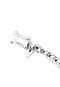 Silverfärgad armband med sammanlänkade länkar, med en slät, polerad yta och ett dekorativt spänne med en hängtagg och tillverkarens märke.