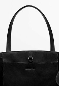Sac tote en cuir noir avec deux longues poignées, une poche avant fermée par un fermoir en métal et un logo embossé sur la partie inférieure avant.