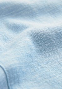 Lichtblau linnen stof met een gestructureerd oppervlak, met een zachte, iets gekreukte uitstraling en een matte afwerking.