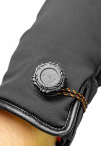 Schwarzer isolierter Handschuh mit einem kreisförmigen, strukturierten Verschluss und orangefarbigem Akzentkordel. Verfügt über glattes, elegantes Material und genähte Kanten.