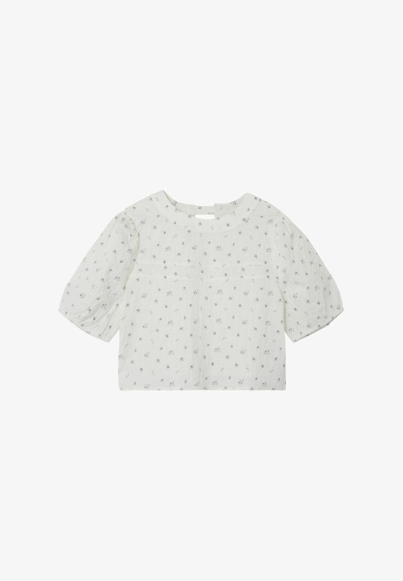 Blusa bianca a maniche corte con piccoli motivi floreali blu, scollatura ampia e vestibilità ampia, realizzata in tessuto leggero con dettagli testurizzati.