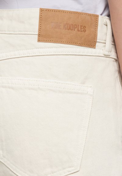 Beli denim hlače z usnjenim označevalcem prišit na pasu, z enim zadnjim žepom in diagonalnim šivom.