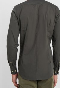 Donkergrijze shirt met lange mouwen, knoopmanchetten, getailleerde pasvorm, gladde textuur en een schone achterkant. Geen zichtbare logo's of patronen.