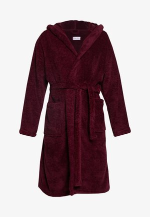 Accappatoio borgogna con cappuccio realizzato in morbido tessuto peluche, dotato di due tasche frontali e una cintura abbinata. Maniche lunghe e lunghezza fino al ginocchio.