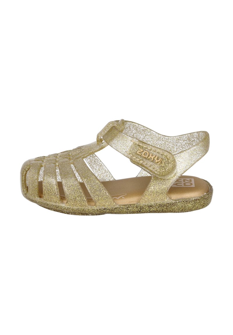 Sandalias doradas brillantes con diseño abierto, cinta alrededor del tobillo y recortes decorativos. Suela texturizada y marca en el lateral.