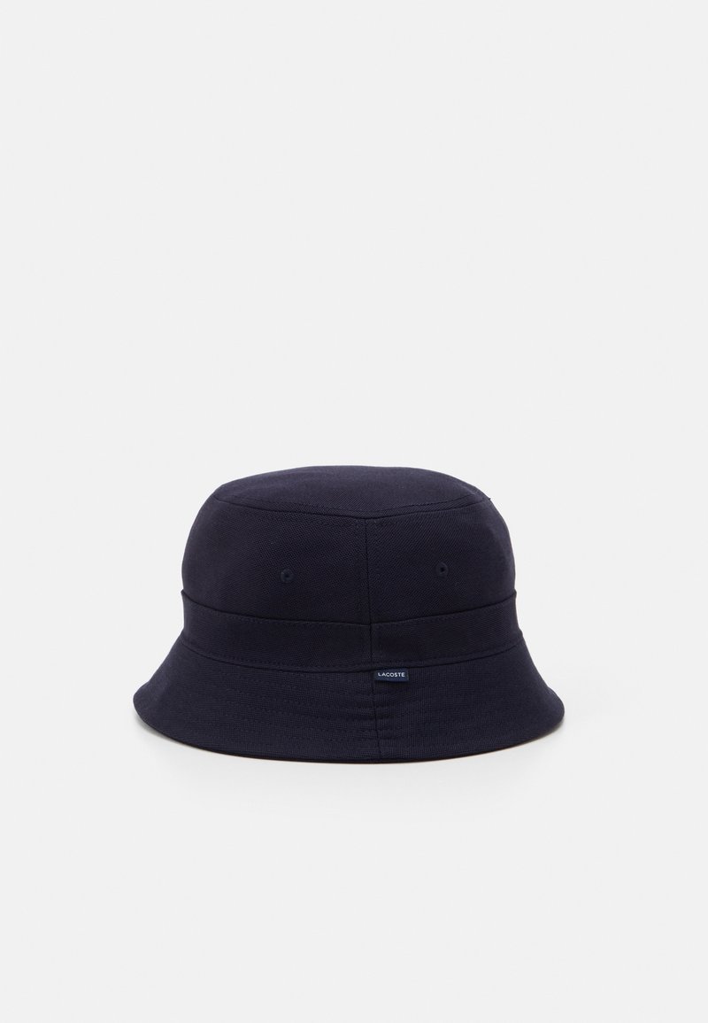 Dunkelblaues Bucket Hat aus strukturiertem Stoff, mit breiter Krempe, zwei Belüftungslöchern und einem kleinen Logostreifen an der Seite.