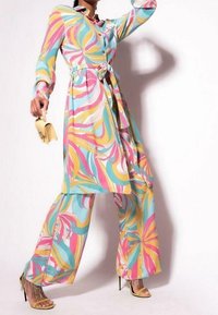 Kleurvolle jurk met lange mouwen met wervelende roze, gele en blauwe patronen, een getailleerde taille, bijpassende broek met wijd uitlopende pijpen en stiletto-hakken.