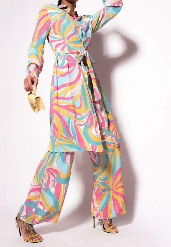 Kleurvolle jurk met lange mouwen met wervelende roze, gele en blauwe patronen, een getailleerde taille, bijpassende broek met wijd uitlopende pijpen en stiletto-hakken.
