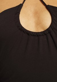 Top halter preto com decote arredondado e tecido franzido. Textura suave e design minimalista, adequado para uso casual.